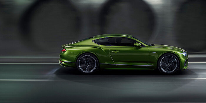  Bentley Birmingham Bentley Continental GT coupe in Tourmaline Green paint driving in profile on a dark road