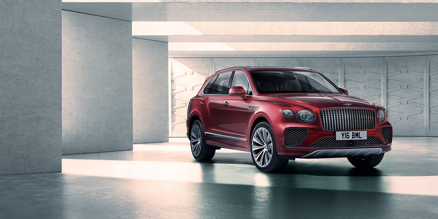 Bentley Birmingham Bentley Bentayga Atelier Edition SUV in Rubino Red paint front three quarter against textured concrete wall