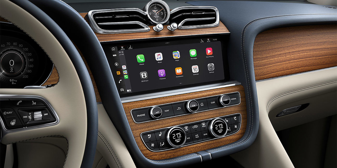 Bentley Birmingham Bentley Bentayga EWB Azure dashboard in Open Pore Koa veneer featuring multimedia screen and climate control console.