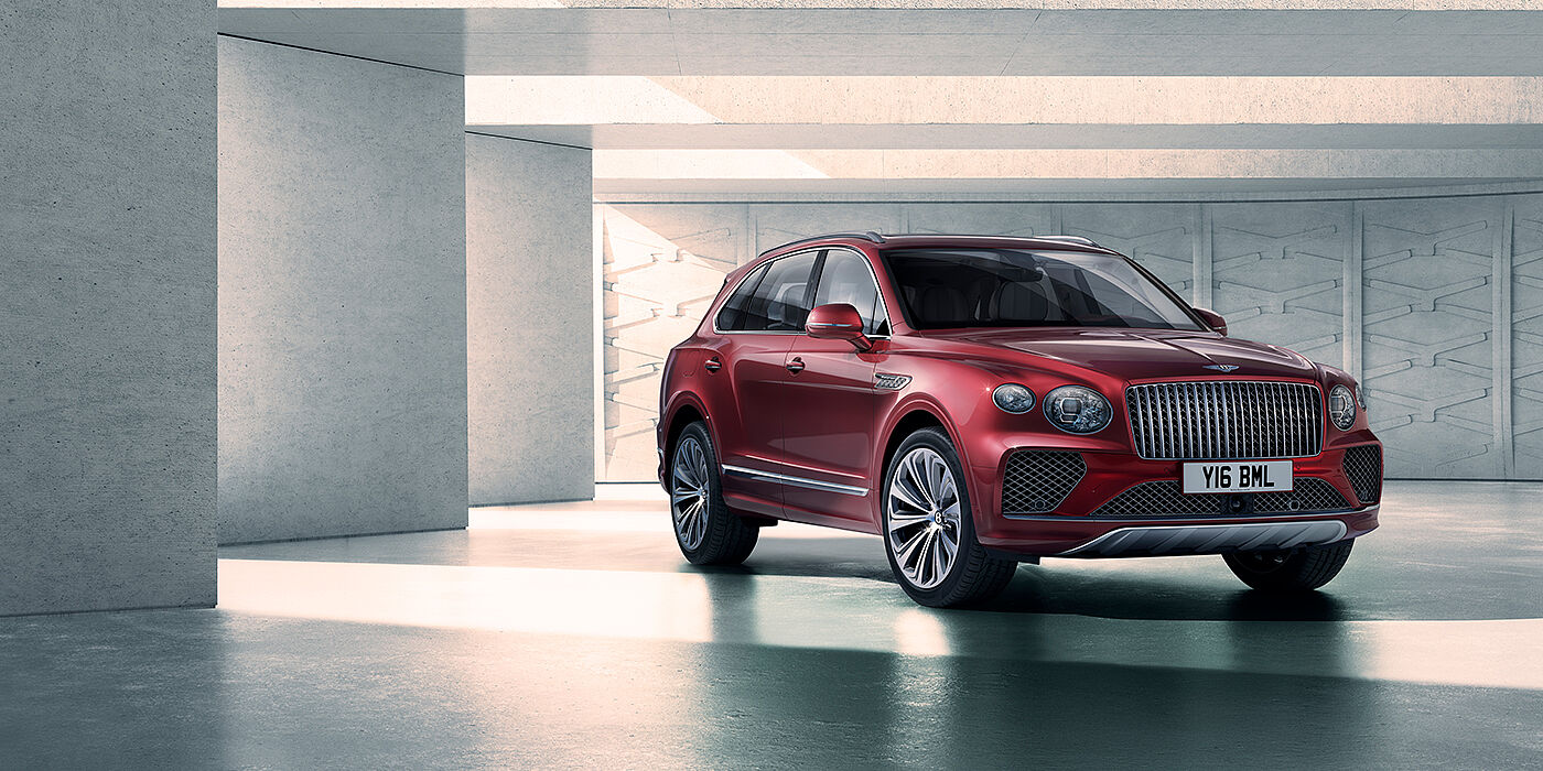 Bentley Birmingham Bentley Bentayga Atelier Edition SUV in Rubino Red paint front three quarter against textured concrete wall