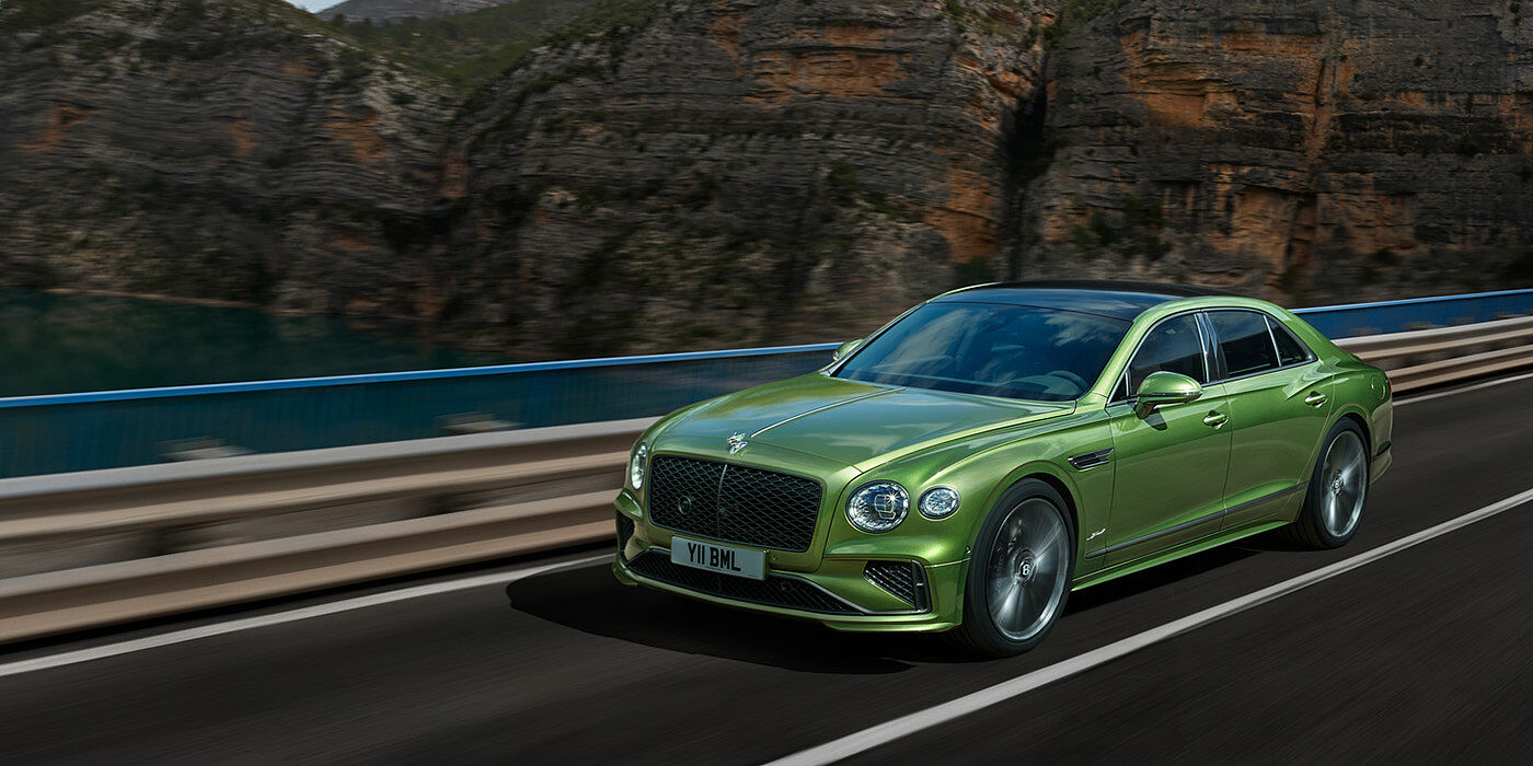 Bentley Birmingham Bentley New Flying Spur Speed v8 hybrid sedan driving dynamically on a mountain road in Tourmaline Green paint
