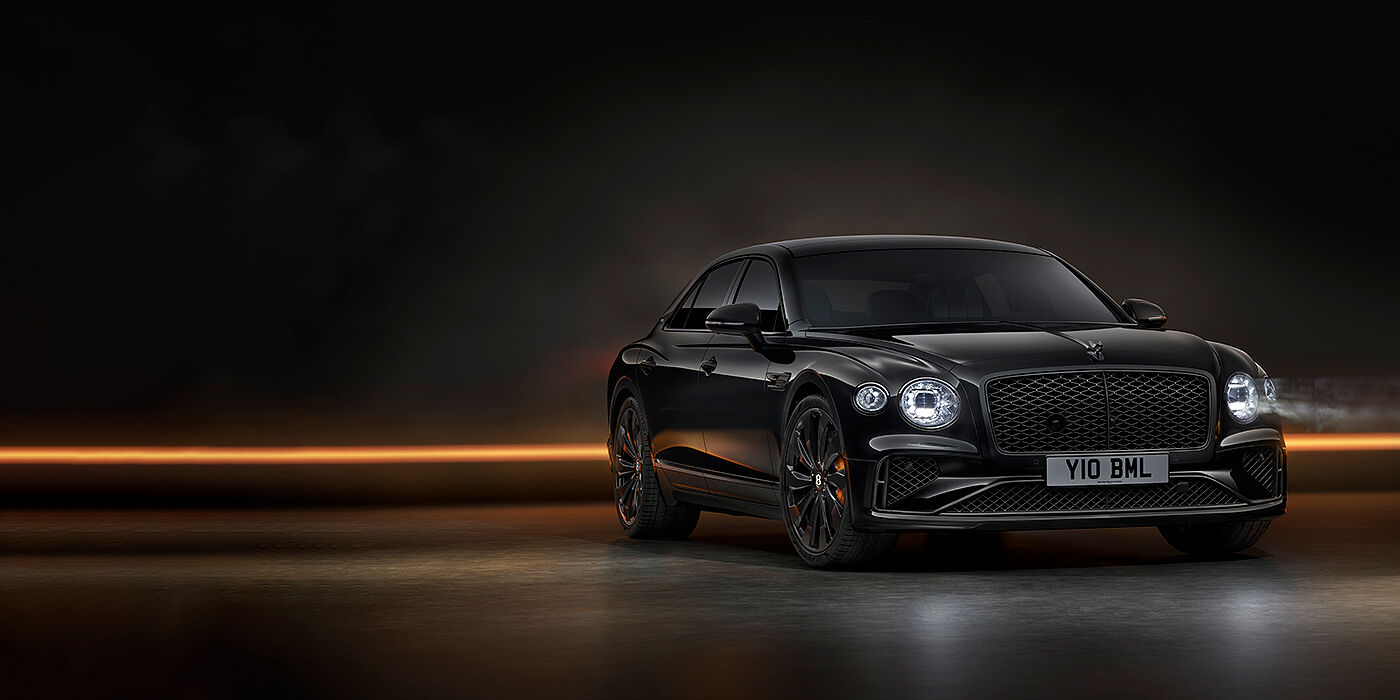 Bentley Birmingham Bentley Flying Spur Black Edition sedan in Black Crystal paint against a dark grey and copper coloured background