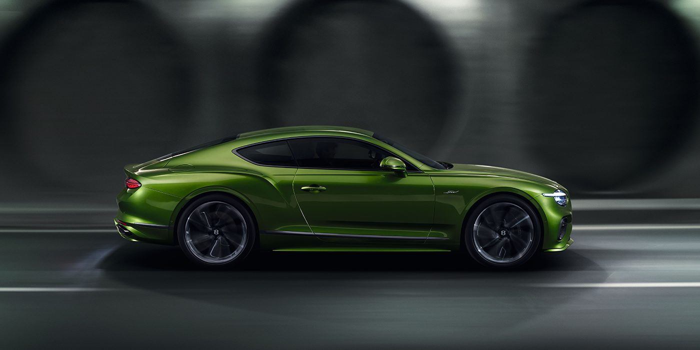 Bentley Birmingham Bentley Continental GT coupe in Tourmaline Green paint driving in profile on a dark road