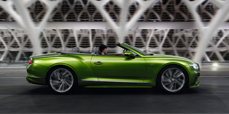 Bentley Birmingham Bentley Continental GTC Speed convertible side profile in Tourmaline Green paint driving dynamically on a bridge at night