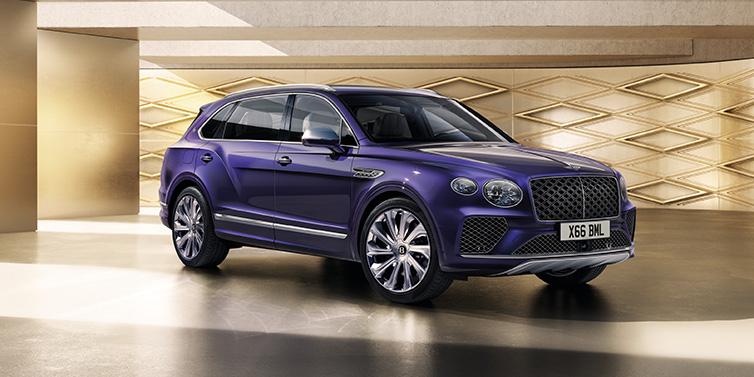 Bentley Birmingham Bentley Bentayga Extended Wheelbase Mulliner SUV front three quarter in Tanzanite Purple paint with a gold patterned background