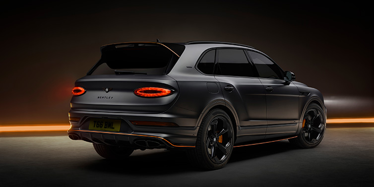 Bentley Birmingham Bentley Bentayga S Black Edition SUV rear three quarter in Anthracite Satin paint against a dark red and yellow background