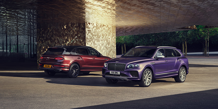 Bentley Birmingham A duo of Bentley Bentayga Extended Wheelbase Mulliner SUVs parked in a city environment, with Tanzanite Purple and Cricket Ball red exterior paint